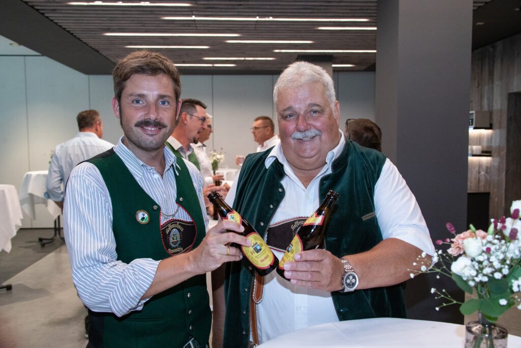 Zwei Gäste in Tracht stoßen mit Bier an